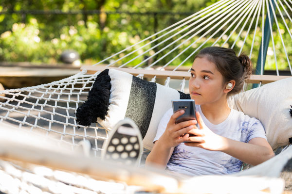 Young girl lying in a hammock enjoying wireless audio through aptX Bluetooth technology
