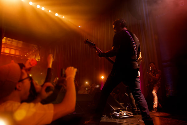 Musicians play on a stage surrounded by fans